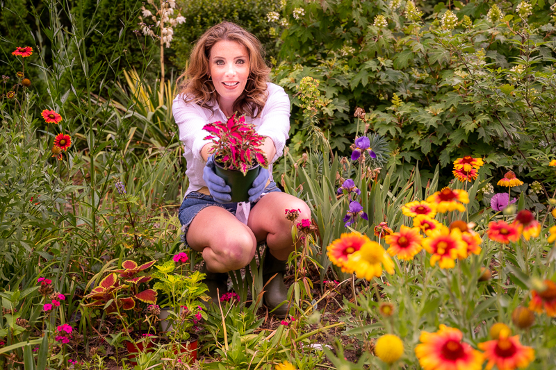 Woman in a garden setting surrounded by annual and perennial plants.